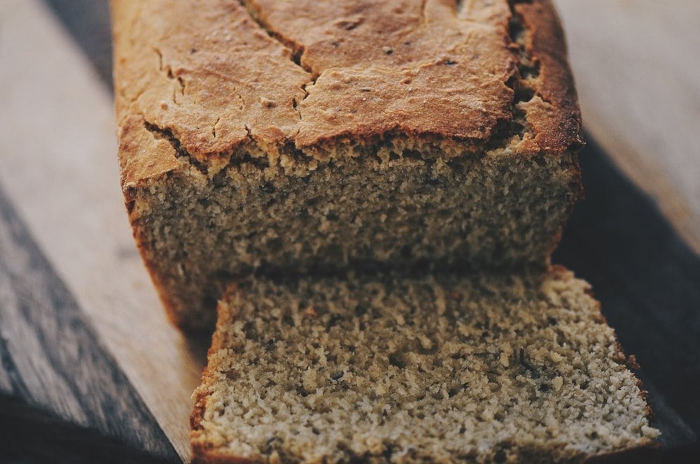 view of rustic loaf of gf bread with one slice in front