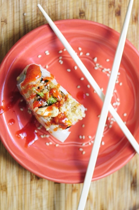 a spring roll on a plate next to chopsticks and sprinkled with sesame seeds