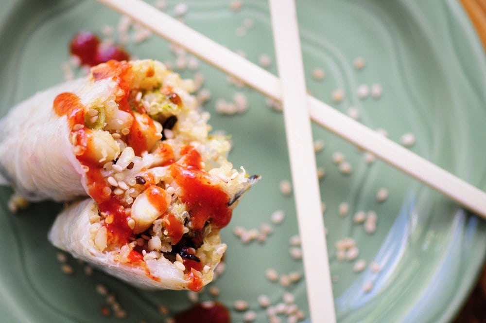 two spring rolls leaning on each other next to a pair of chopsticks