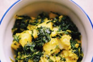 a top view of white bowl filled with kale potato curry
