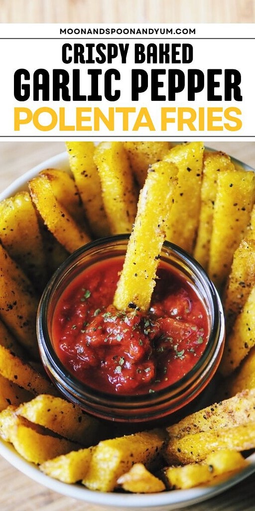 A bowl of crispy baked polenta fries, seasoned with garlic and pepper, arranged around a small bowl of red dipping sauce for a delicious snack.