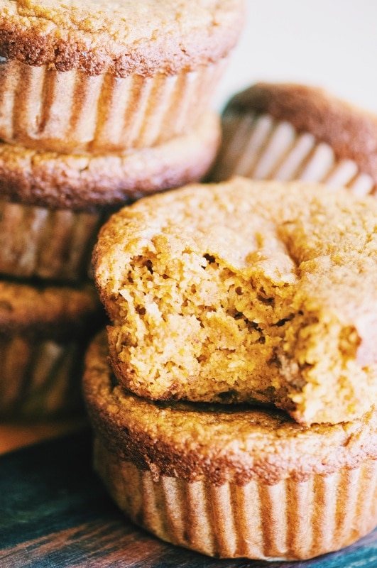 A stack of brown orange muffins with a bite taken out.