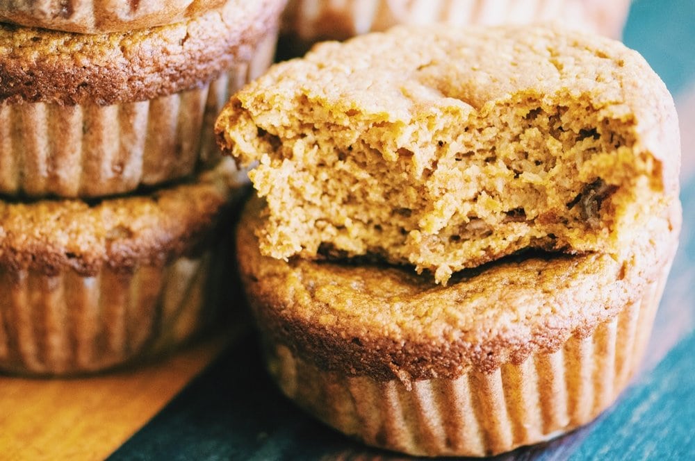 A stack of light brown gluten free pumpkin muffins.