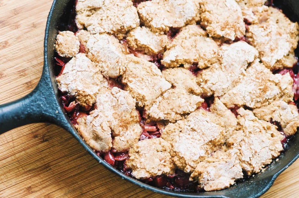 A cast iron skillet filled with a baked cobbler.