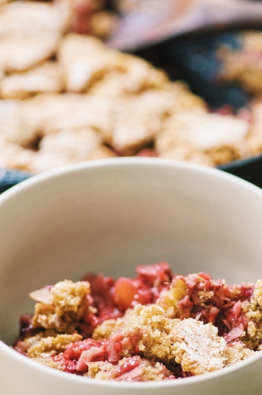 A white ceramic bowl filled with tan cooked dough and pink berries.