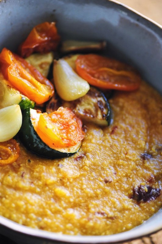  A warm, hearty, and nourishing bowl of grits (polenta) chock full of pumpkin, chipotle peppers, and sharp cheddar cheese. This beautiful gluten-free vegetarian dish is topped off with tender and nutritious garlic roasted vegetables. A perfect autumn meal! #grits #pumpkin #pumpkingrits #pumpkinchipotle #cheesy #polenta #garlic #roastedveggies #autumn #halloween #brunch 