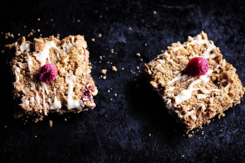  These Raspberry Gingerbread Crumble Bars are made with a delectably spiced buttery oat crust filled with a luscious raspberry chia seed jam and then drizzled with white chocolate! They make for one beautiful, easy, delicious and festive gluten-free treat! #raspberrybars #gingerbreadbars #glutenfreebars #gingerbread #chiaseedbars #whitechocolate #chiajam 
