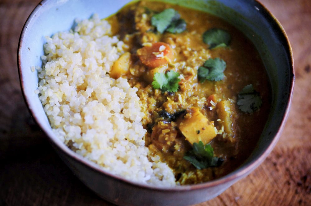 A ceramic bowl filled with half quinoa, half curry.