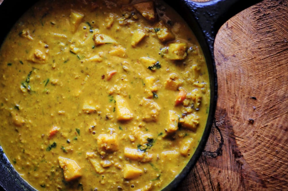 A cast iron skillet filled with a yellow curry.