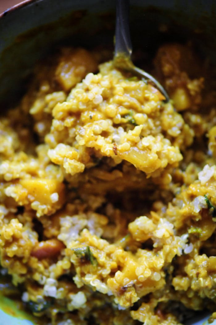 A close view of quinoa and cauliflower rice coated in a yellow coconut curry sauce.