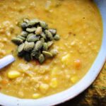 a large bowl of vegan corn chowder topped with pumpkin seeds