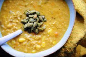 a large bowl of vegan corn chowder topped with pumpkin seeds