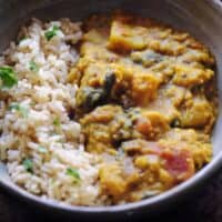 a white bowl with rice and potato lentil curry on dark cookie sheet backdrop