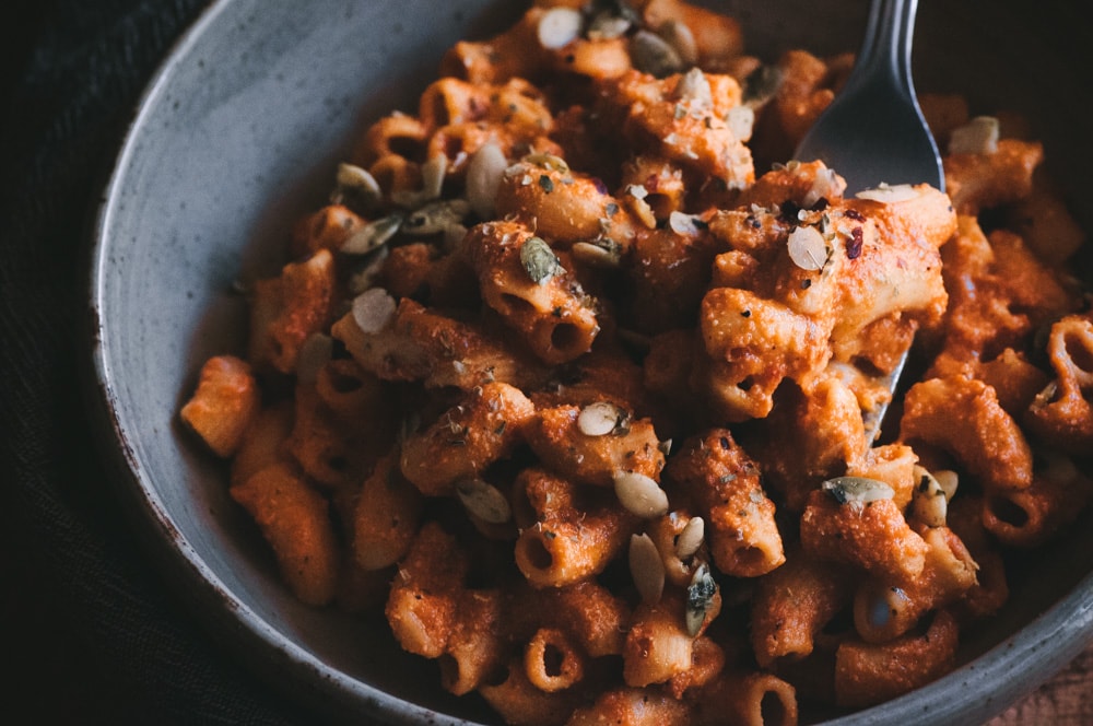  This gluten-free and vegan pasta dish is bursting with flavorful roasted red peppers, ground chipotle pepper and its secret ingredient of pumpkin seed milk! Topped off with pepitas, cilantro, red chili flakes and nutritional yeast, it makes for one big, spicy and delicious bowl of healthy comfort food. #pumpkinseedmilk #spicypasta #chipotlepasta #roastedredpeppersauce #glutenfreepasta #veganpasta #vegancomfortfood #pepitas 