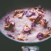 a close up of rose petals resting on a chai latte