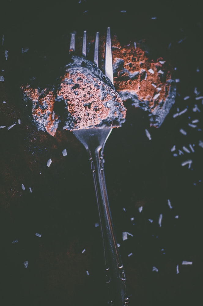 A silver fork with a piece of blue pancake resting on top.