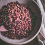 a top view of a big white bowl filled with cooked red quinoa