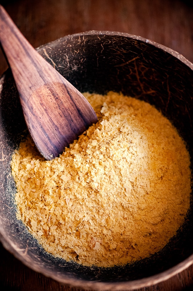 A dark wood bowl filled with yellow powder.