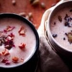 two mugs of seed cycling moon milk topped with rose petals lavender and seeds