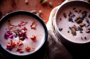 two mugs of seed cycling moon milk topped with rose petals lavender and seeds