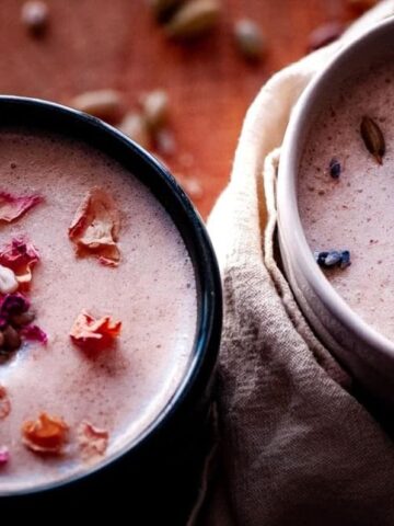 two mugs of seed cycling moon milk topped with rose petals lavender and seeds