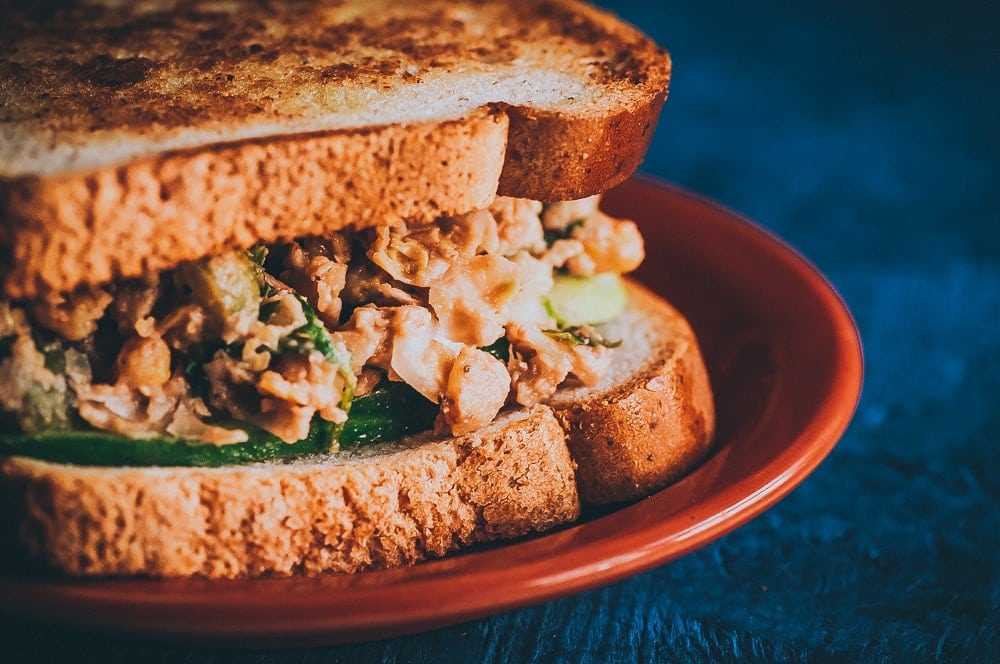  This Zesty Smashed Chickpea Salad Sandwich only take a QUICK 10 minutes to throw together, is gluten-free + vegan, healthy, high in protein + fiber , and SUPER flavorful! It makes a great lunch, dinner or picnic dish! #chickpeasalad #vegansandwich #chickpeasaladsandwich #smashedchickpeasalad #smashedchickpeasaladsandwich 