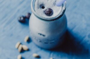 an image of a glass filled with blueberry moon milk on blue wooden background