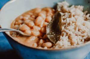 a close up of light green bowl filled with rice peruvian beans and bay leaf