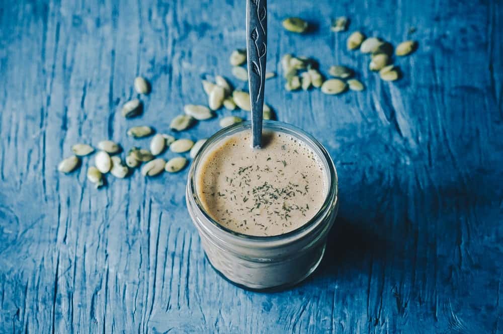 vegan ranch dressing in a glass jar surrounded with seeds