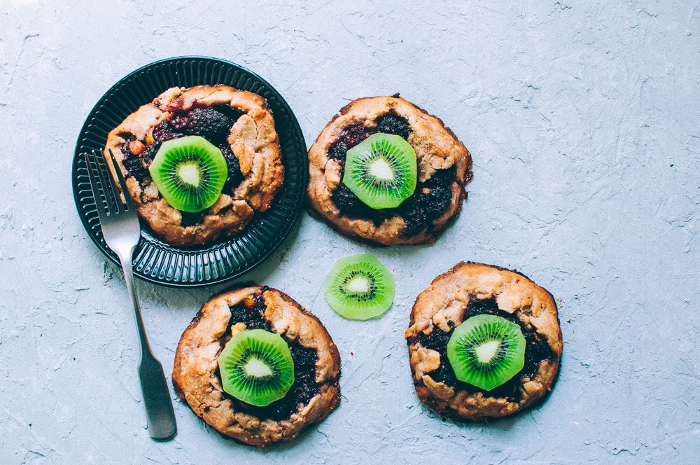   These gluten-free vegan mini rustic pies are filled with juicy blackberries and tart kiwi for a fun twist! Easy, healthy, and delicious galettes are at your fingertips! #galette #galettes #minipies #rusticepies #kiwi #blackberries #glutenfreepie #veganpie #kiwipie  