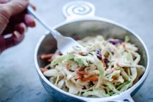 a pewter bowl filled with vegan coleslaw