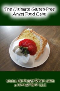 A slice of gluten-free angel food cake topped with whipped cream and sliced strawberries on a white plate, showcasing one of the finest tapioca flour recipes. Text reads "The Ultimate Gluten-Free Angel Food Cake" and "www.Heritage-River.com © Heritage River LLC".