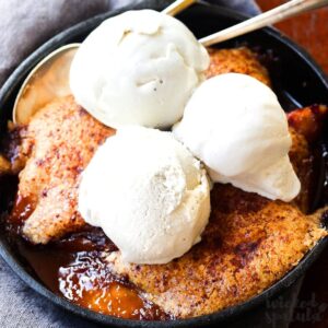 A skillet dessert topped with three scoops of vanilla ice cream, featuring a golden-brown crust made from one of our favorite tapioca flour recipes. Two spoons are placed in the dish, ready for sharing.