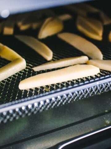 a close up image of french fries on the tray of cosori air fryer toaster oven