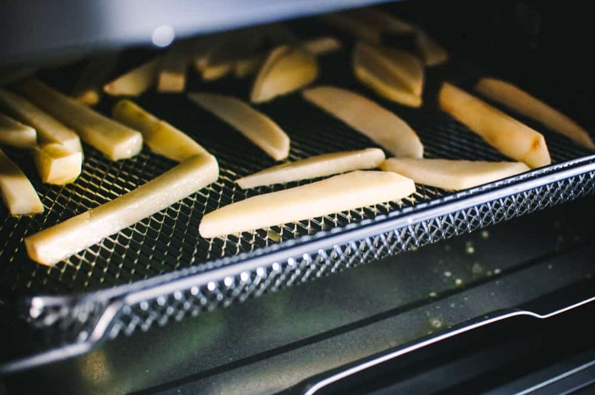 a close up image of french fries on the tray of cosori air fryer toaster oven