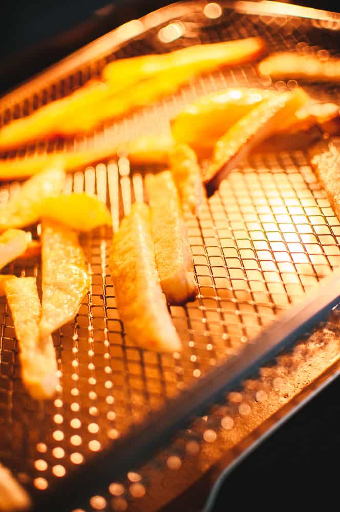 a close up of french fries in an air fryer basket