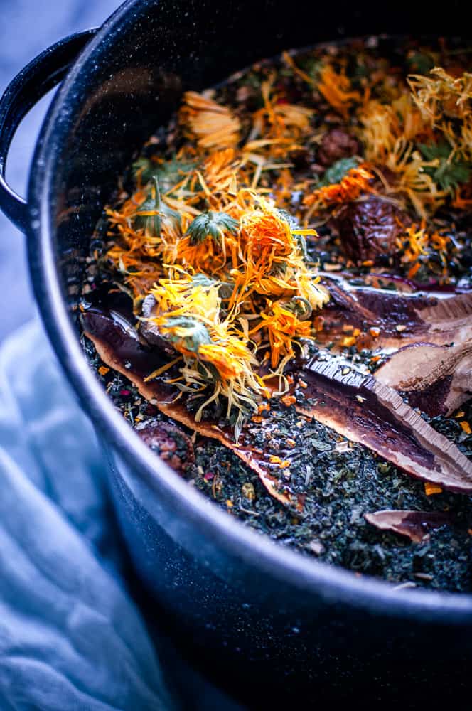 a close up shot a stock pot filled to the brim with mushrooms herbs spices and flower