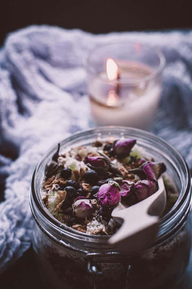 a closeup of wooden scoop dipped into a jar of fizzy bath salts