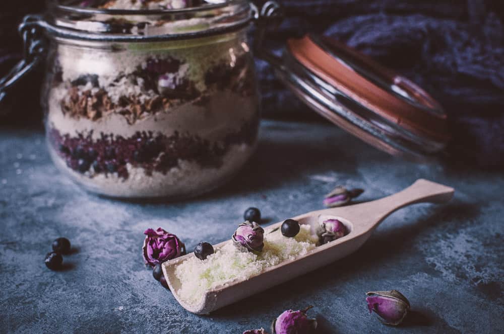 a wooden scoop filled with bath salts juniper rose