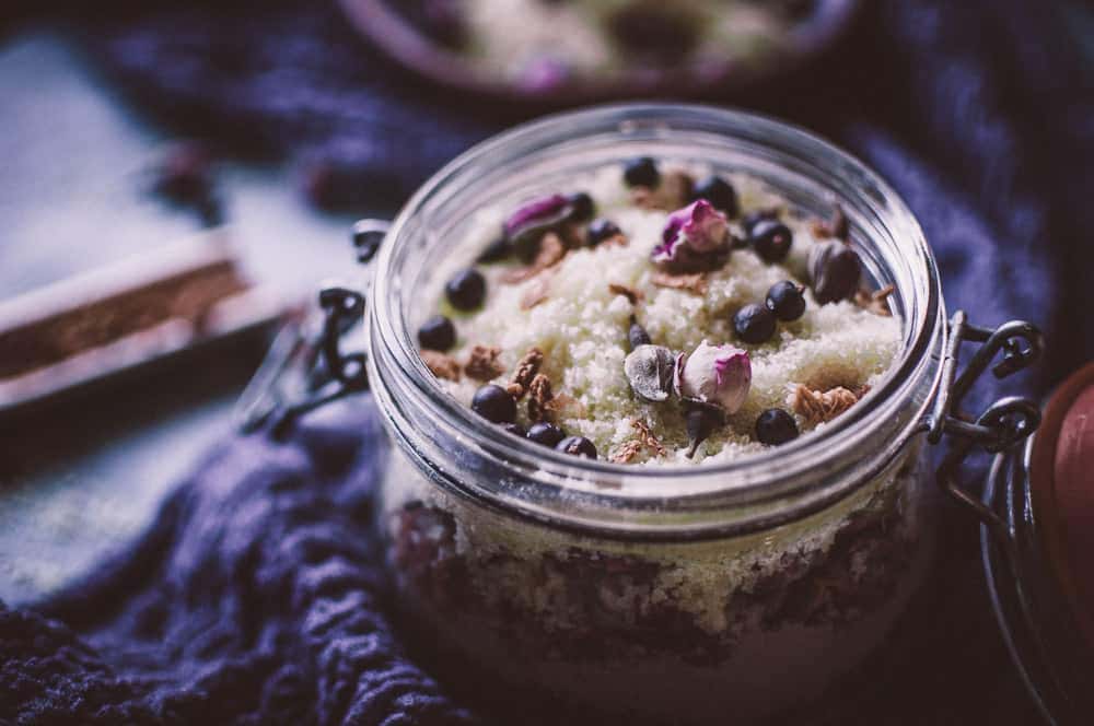 a jar of bath soak topped with rose buds