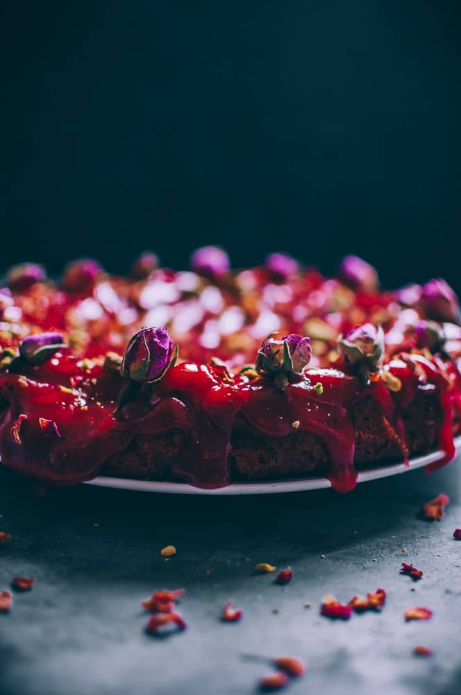 side view of red cake topped with rose buds