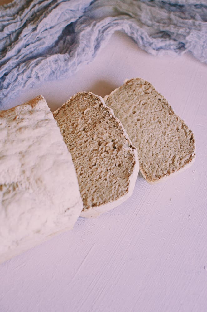 a cut loaf of vegan gluten free bread next to purple table runner