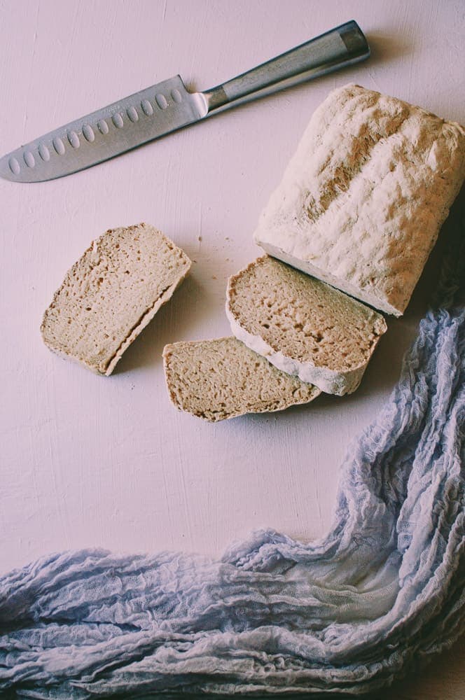 a cut loaf of bread on pink backdrop next to purple gauxe cloth