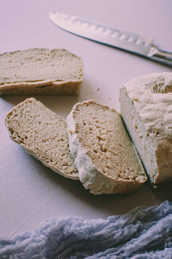 a cut loaf of gluten free bread on pale pink backdrop