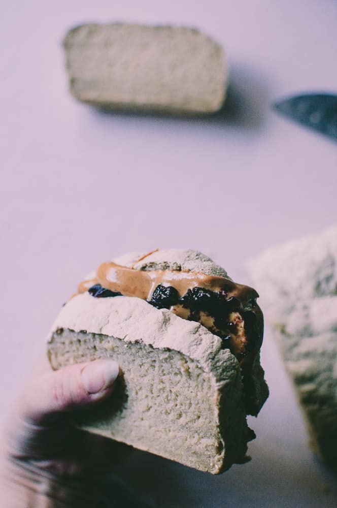a hand holding a gluten free vegan peanut butter and jelly sandwich