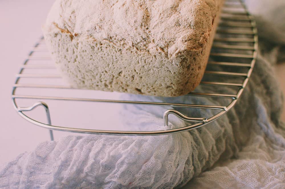 a loaf of gluten free sandwich bread resting a on a wire cooling rack