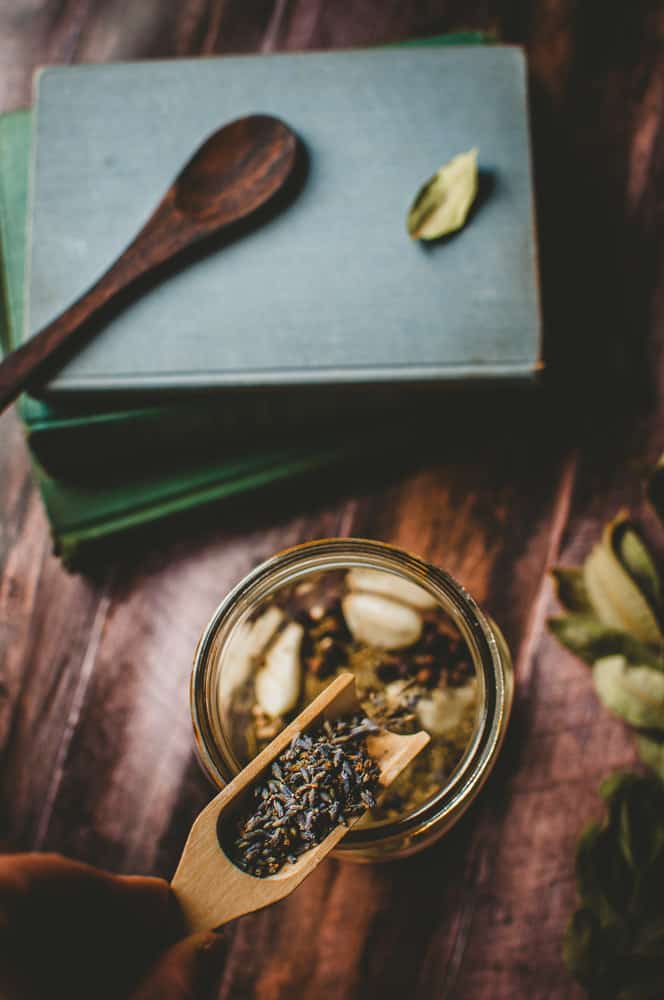 a hand holding a wooden scoop filled with dried lavender buds