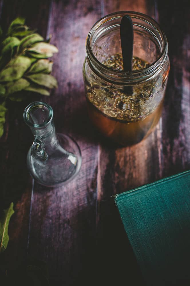 a potion bottle next to a canning jar filled with four thieves vinegar