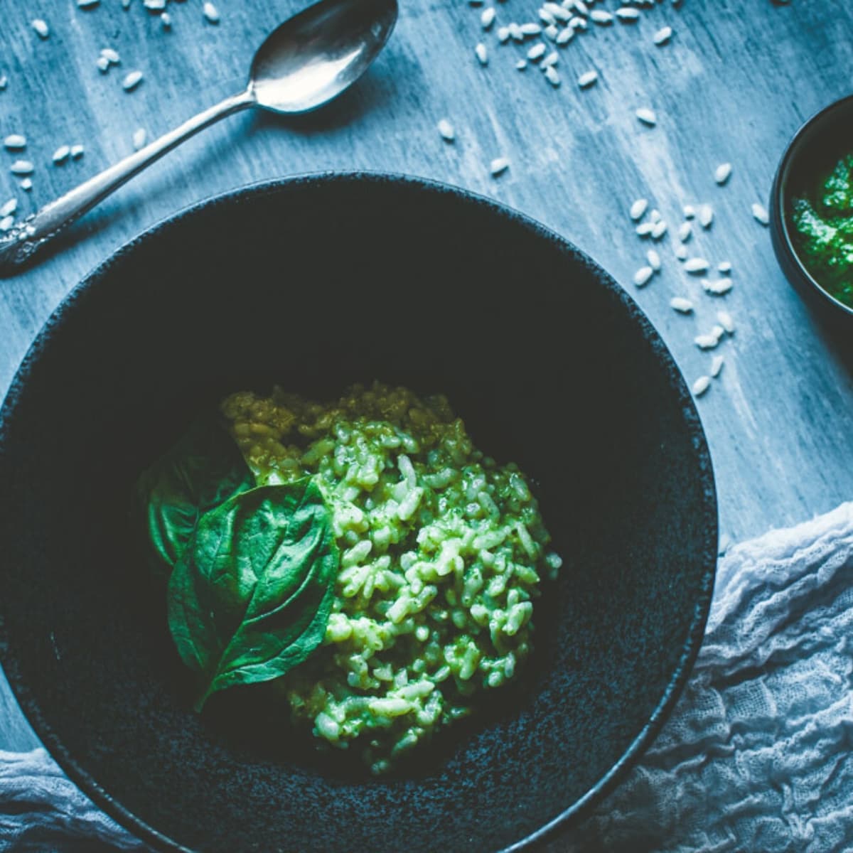 A black bowl filled with green risotto.