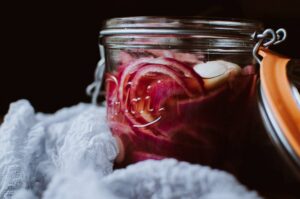 a side shot of a jar filled with pickled red onions